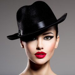 Wall Mural - Сlose-up portrait of a woman in a black hat  with red lips