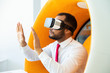 © Mangostar - Focused businessman in VR headset. Serious young African American businessman sitting in spherical chair and using virtual reality headset. Technology concept