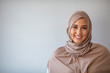 © Dragana Gordic - Young asian muslim woman in head scarf smile with arms crossed. Portrait of young muslim woman wearing hijab head scarf at gray background. Portrait of beautiful Muslim woman on grey background