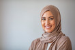 Woman in traditional Muslim clothing, smiling. Woman headshot looking at camera and wearing a hijab. Arabian woman with happy smile. Strict formal outfit and elegant appearance. Islamic fashion.