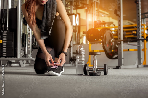Fitness woman tying shoelaces before exercise workout at gym Tableau sur Toile