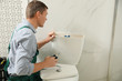 © New Africa - Professional plumber repairing toilet bowl in bathroom