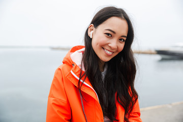 Sticker - Smiling attractive young asian woman wearing raincoat