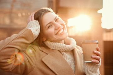 Canvas Print - Young woman with cup of coffee on city street in morning