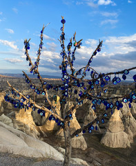 Wall Mural - Nazar amulets hang on a tree against a background of a valley of rocks. Cappadocia, Turkey. UNESCO World Heritage. 05 december 2019