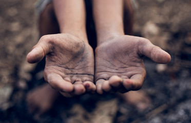 poor child or beggar begging you for help sitting at dirty slum. concept for poverty or hunger people,human rights,donate and charity for underprivileged children in third world 