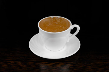 black coffee pour into a white mug on a dark background