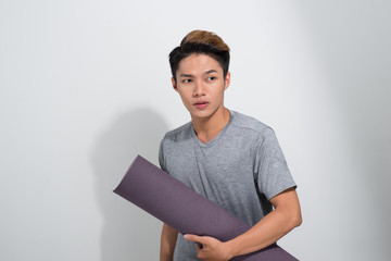 Wall Mural - Asian fitness man with yoga mat standing on white background