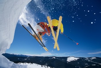 Skiers Launching Off Snow Bank Hitting The Slopes