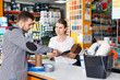 © JackF - Young female seller standing at the counter in household tools store