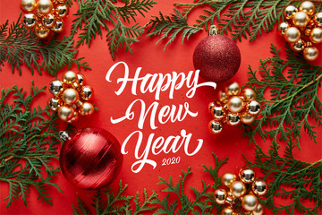 Canvas Print - top view of shiny Christmas decoration and thuja on red background with happy new year lettering