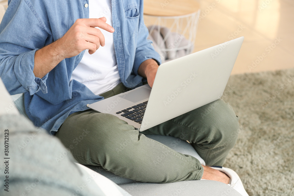 Handsome man with laptop on sofa at home