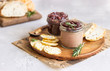 Fresh homemade chicken liver pate and onion chutney (marmalade) in a jar, bread and crackers on a wooden plate. Light grey background, selective focus.