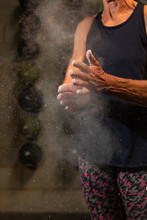 An Anonymous Fit Woman In Her Seventies Claps Chalk Off Of Her Hands While Working Out At A Gym.