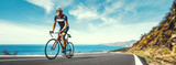 Mature Adult on a racing bike climbing the hill at mediterranean sea landscape coastal road