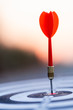 © Zenzeta - Close up red dart arrow hitting target center dartboard on sunset background. Business targeting and focus concept.