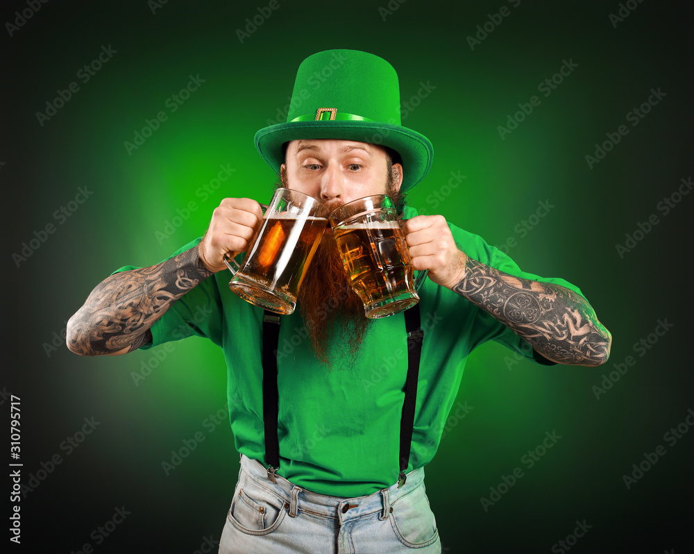 Bearded man with glasses of beer on dark background. St. Patrick's Day celebration