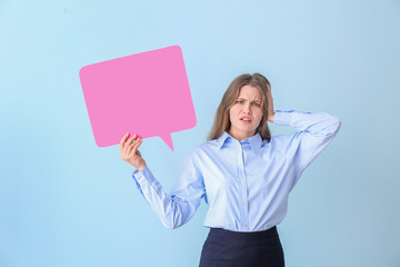 Wall Mural - Confused young businesswoman with blank speech bubble on color background