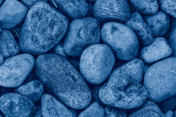 Closeup macro of big huge large blue stones rocks pebbles lying on ground. Natural eco environmental background texture. View from top above. Toned with classic blue 2020 colour.