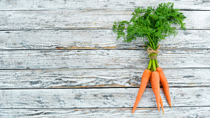 Wall Mural - Fresh carrots on a white wooden background. Top view. Free space for your text.