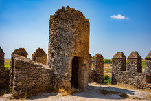The Abandoned Stone Aguzaderas Castle In El Coronil, Spain, A Ruined 14th Century Morrish Castle, Rests In A Field Of Sunflowers On A Cloudless, Summer Day.
