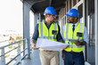 © Rido - Architects discussing plan at construction site