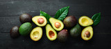 Fototapeta  - Fresh avocado with leaves on a black background. Top view. Free space for your text.