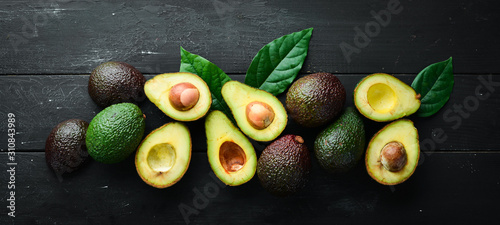 Cuadros en Lienzo Fresh avocado with leaves on a black background