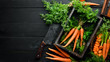 Fresh carrots on a black wooden background. Top view.