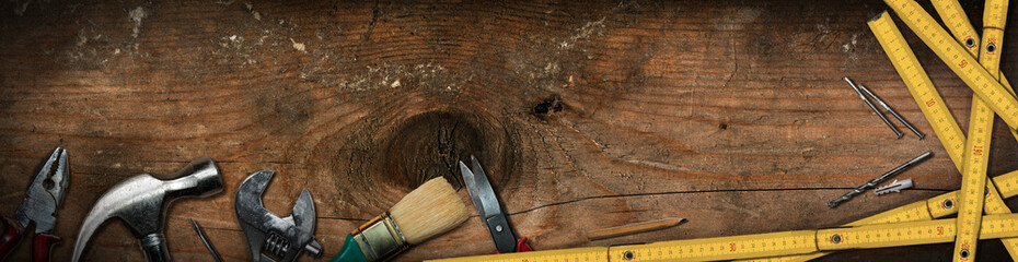 Group of hand tools on a wooden work table with copy space and dark shadows. Home improvement and do it yourself concept