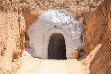 Closeup view of entrance of small underground troglodytes traditional house situated in Sahara desert. Horisontal color photography.