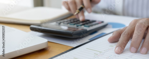 Fotografía Close-up of businessman hand using calculator to calculate business data, accountancy document at home office