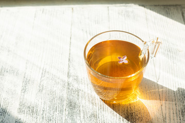 Cup of herbal tea on wooden background. Glass cup. Rays of sunlight