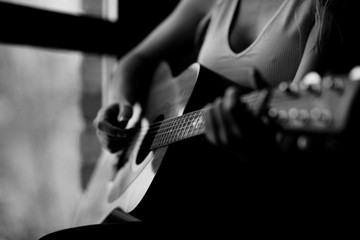 girl plays the guitar near the window in a white T-shirt black and white