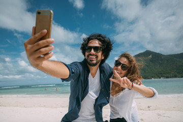 A pair of lovers take a selfie on a tropical beach.