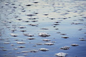 Spiegelung von Schaumblasen im Wattenmeer