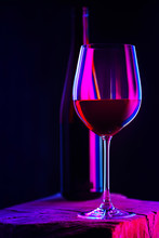 Glass Of Red Wine With Bottle On Wooden Table And Dark Background