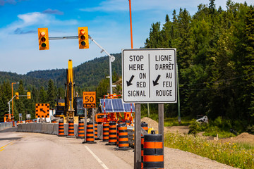 Wall Mural - A close up view of a stop here on red signal sign in french and english, major roadworks and infrastructure improvements in Canada, with copy space