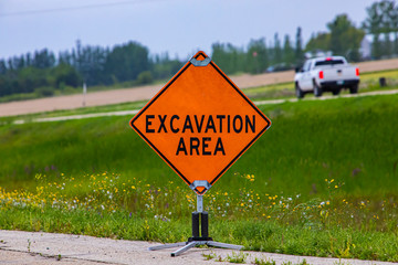 Wall Mural - A close up of a motorist beware warning sign near a roadside excavation area, with blurred truck and grass verge in the background with copy space