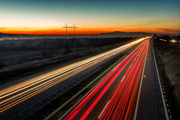 Cars light trails on a straight highway at sunset. Night traffic trails, Motion blur, Night city road with traffic headlight motion. 