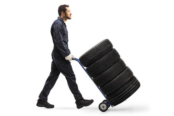 Canvas Print - Mechanic pushing car tires on a hand truck