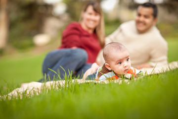 Wall Mural - Happy Crawling Baby Boy and Mixed Race Parents Playing in the Park