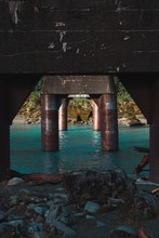 Vertical Shot Of The Metallic Pile Bridge And The Blue River From The Shore