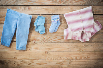 Sticker - baby clothes hanging on  rope on wooden background