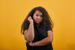 Disappointed curly afro-american young woman with overweight keeping fist up, serious over isolated orange background wearing fashion black shirt. People lifestyle concept.