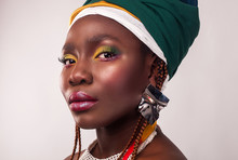Studio Portrait Of African Young Woman With Vibrant Makeup Of Yellow And Green Colors. Colorful Ethnic Headwrap.