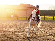 8 Year Boy Riding White Horse During Sunset At Ranch