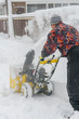 © jollier_ - man operating snow blower to remove snow on driveway. Man using a snowblower. A man cleans snow from sidewalks with snowblower. vertical photo