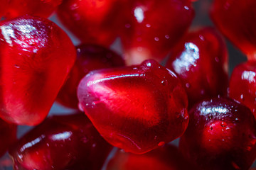 Ripe pomegranate seeds closeup on a dark background. Spectacular macro photo. The concept of wholesome organic food, vegetarianism, fresh fruit harvest.