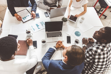 Wall Mural - A team of young office workers, businessmen with laptop working at the table, communicating together in an office. Corporate businessteam and manager in a meeting. coworking.